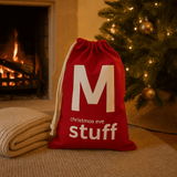 Red bag labeled 'Christmas Eve stuff' in front of a fireplace and Christmas tree.