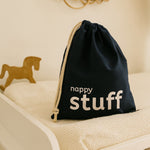 Navy drawstring bag with 'nappy stuff' text on a beige surface