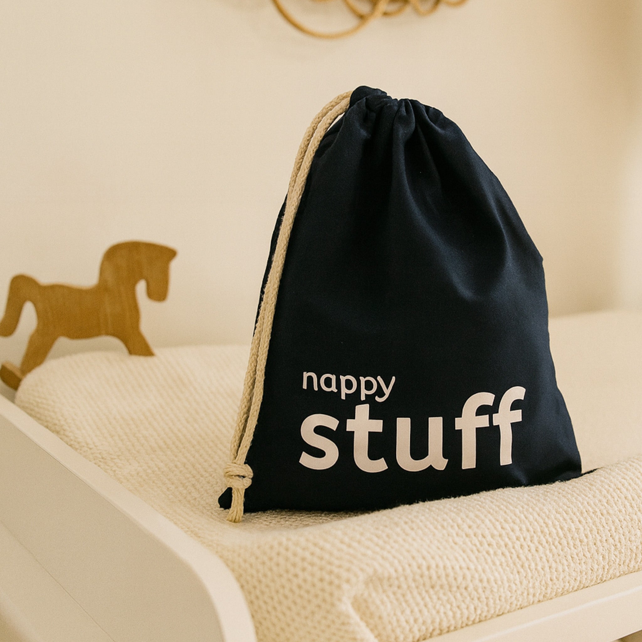 Navy drawstring bag with 'nappy stuff' text on a beige surface