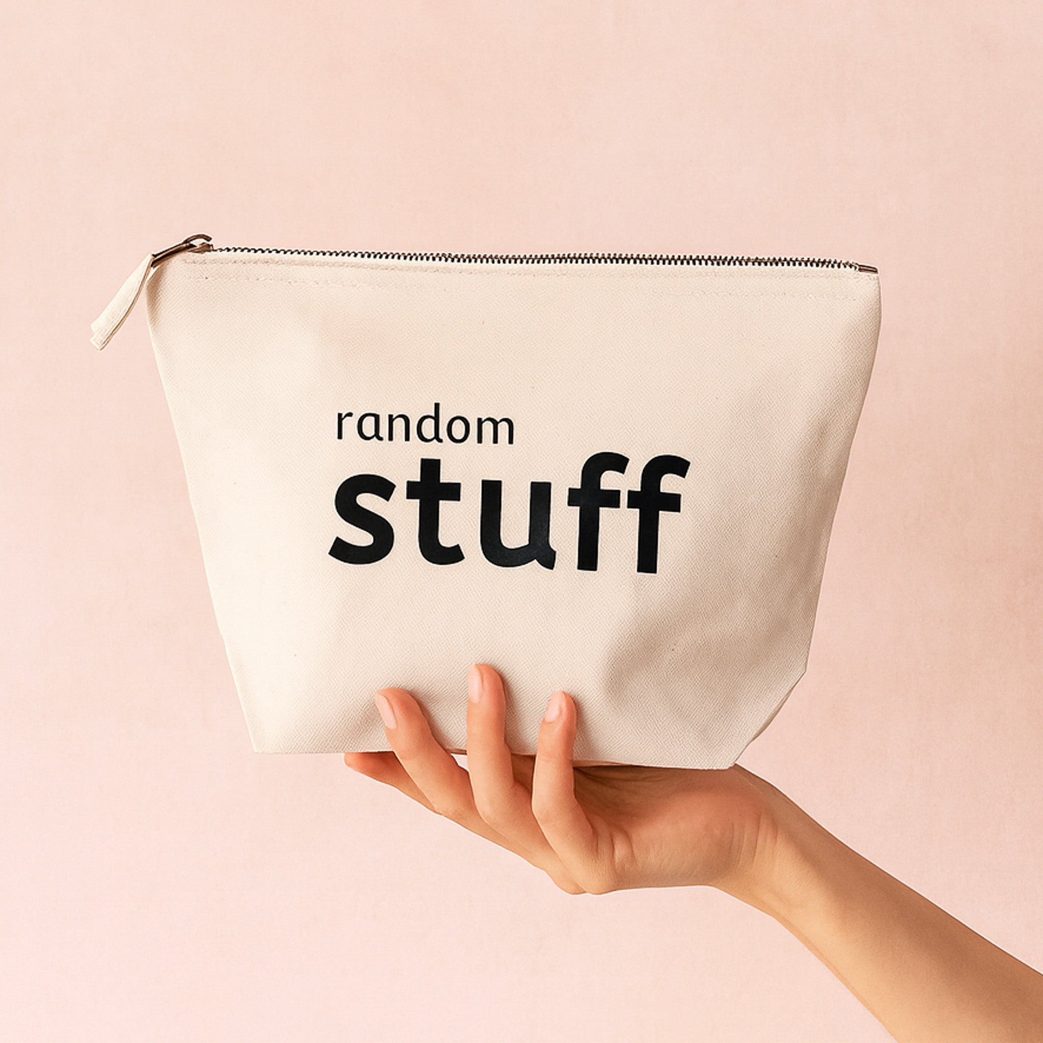 Natural pouch with 'random stuff' text held by a hand on a pink background